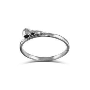 Könnte beinhalten: Ein silberner Ring mit einem kleinen Vogel Schädel Design.