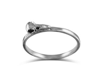 May include: A silver ring with a small bird skull design.
