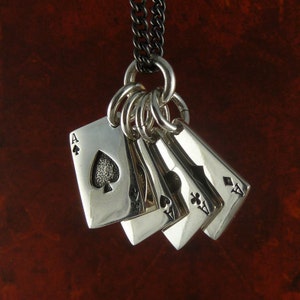 Puede incluir: Collar de plata con un dije de cinco cartas de juego, incluyendo el As de Picas, el As de Corazones, el As de Tr&eacute;boles y el As de Diamantes.