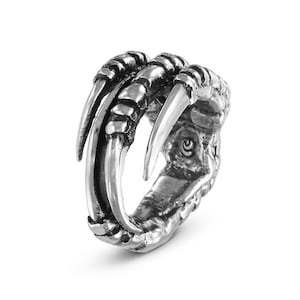 Könnte beinhalten: Ein silberner Ring mit einem detaillierten Design einer Vogelfeder. Der Ring ist aus Metall und hat eine strukturierte Oberfläche.