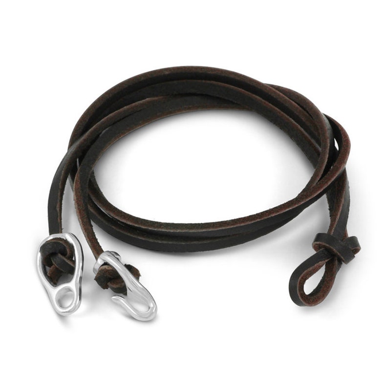 May include: A brown leather bracelet with silver clasps. The bracelet is made of a single strand of leather that is tied together at one end with a knot.