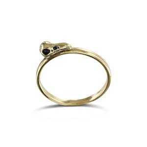 Könnte beinhalten: Ein goldener Ring mit einem kleinen Totenkopf-Design auf der Oberseite.