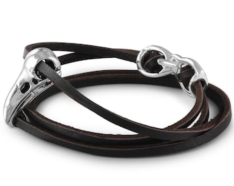 May include: A brown leather wrap bracelet with a silver skull charm and a silver clasp.