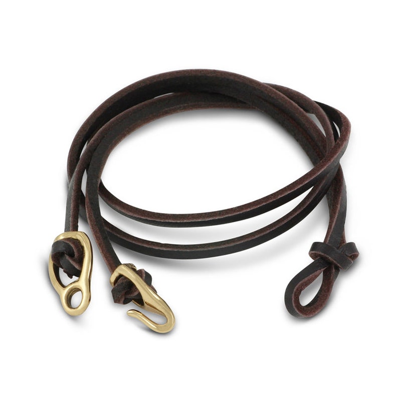 May include: A brown leather bracelet with a gold clasp and a knot at the end.