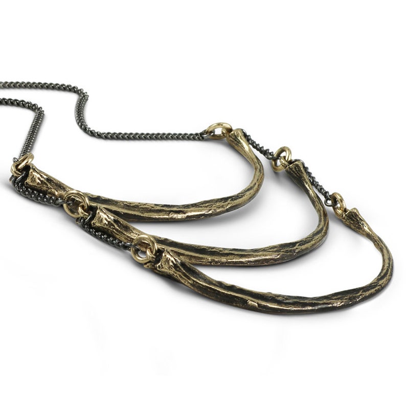 May include: A gold necklace with three curved, textured, brass bars connected by a black chain.