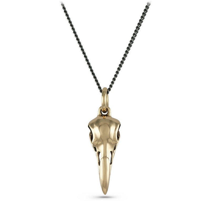May include: A gold bird skull pendant necklace with a black chain.
