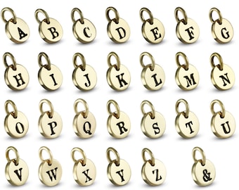 May include: Gold-toned metal alphabet charms with a black enamel finish. Each charm features a letter of the alphabet, from A to Z, and an ampersand symbol.