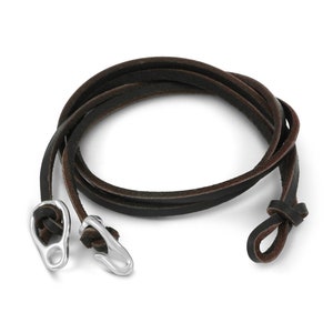 May include: A brown leather cord bracelet with silver metal clasps. The cord is wrapped around itself and the clasps are on either end.