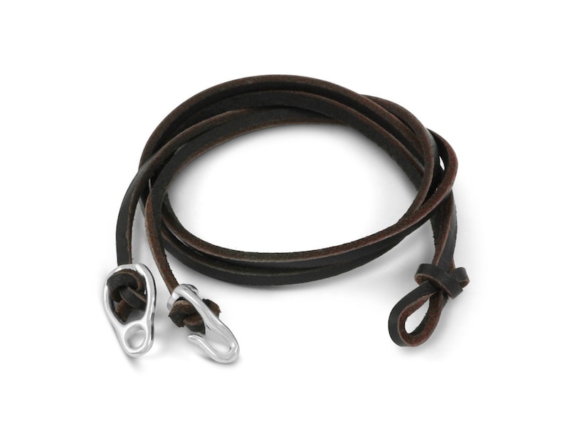 May include: A brown leather cord bracelet with silver metal clasps. The cord is wrapped around itself and the clasps are on either end.