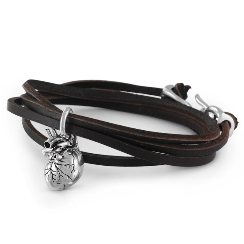 Pu&ograve; includere: Un braccialetto in pelle nera con un ciondolo a forma di cuore anatomico in argento. Il braccialetto ha una chiusura a gancio in argento.