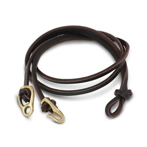 May include: A brown leather bracelet with a gold clasp and a knot at the end.