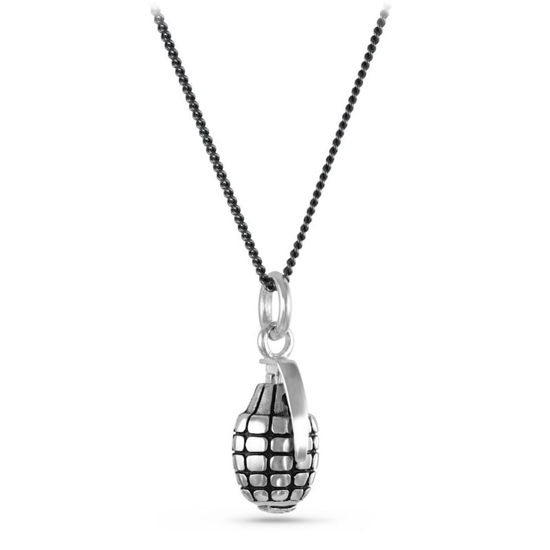 May include: A silver grenade pendant necklace with a black chain. The pendant is detailed with a textured surface and a pin.
