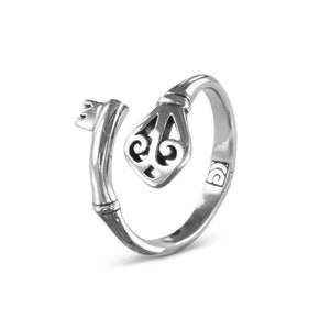 May include: A silver key ring with a detailed key design. The ring is open and ready to be worn.