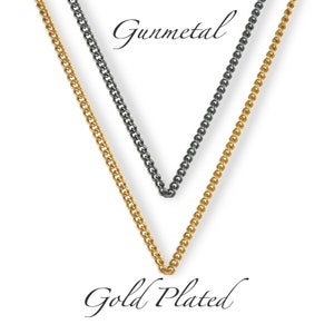 May include: Two chains, one gold plated and one gunmetal, are shown hanging against a white background. The chains are both curb chains.