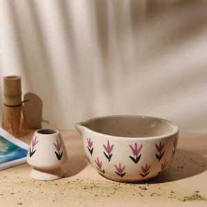 May include: A set of three ceramic mugs with a speckled, matte finish. The mugs are in cream, light grey, and dark grey. Each mug has a simple, minimalist design, ideal for coffee or tea.