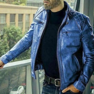 Könnte beinhalten: Blaue Lederjacke mit Steppdesign an den Schultern und Reißverschluss. Die Jacke hat einen klassischen Biker-Stil mit Stehkragen und mehreren Taschen. Getragen über einem schwarzen Hemd und Jeans.