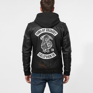 Könnte beinhalten: Schwarze Lederjacke mit schwarzer Kapuze und dem "Sons of Anarchy"-Aufnäher auf dem Rücken. Der Aufnäher zeigt einen Sensenmann mit einer Sense und den Text "California".