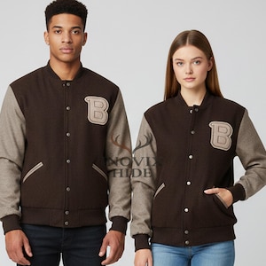 May include: Brown varsity jacket with grey sleeves and a large letter "B" patch. The jacket has a button-up front, side pockets, and ribbed cuffs and hem. The jacket is worn by two people.