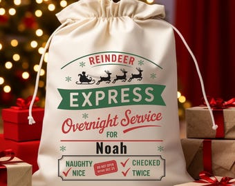 May include: A cream Christmas gift bag with a drawstring. The bag has the text "Reindeer Express Overnight Service for Noah" in green and red. Brown paper-wrapped presents with red ribbon are in front of the bag.