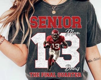 Könnte beinhalten: Ein anthrazitfarbenes T-Shirt mit einem rot-weißen Aufdruck, der die Wörter SENIOR, Mom, Davis und THE FINAL QUARTER zeigt. Das Design enthält eine große weiße Zahl 13 und einen Footballspieler in roter Uniform, der einen Football hält.