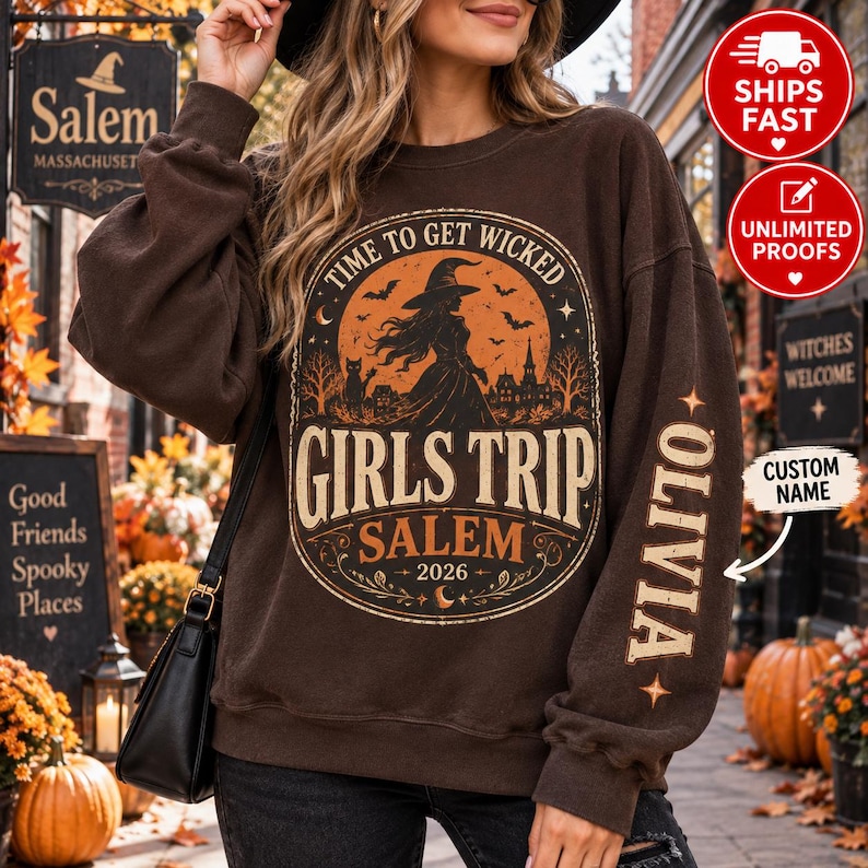 May include: A dark brown crewneck sweatshirt featuring a graphic of a witch, bats, and a haunted house inside an orange moon. The text reads Time to Get Wicked, Girls Trip, Salem, 2026. The name Olivia is printed vertically on the left sleeve.