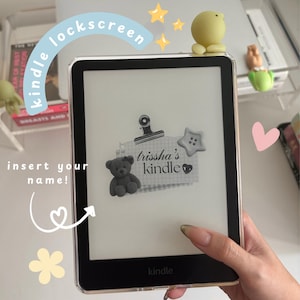 May include: A Kindle e-reader in a clear case, displaying a custom lockscreen. The design includes a teddy bear, a star-shaped button, and the text "trissha's kindle". The words "kindle lockscreen" and "insert your name!" are also visible on the screen.
