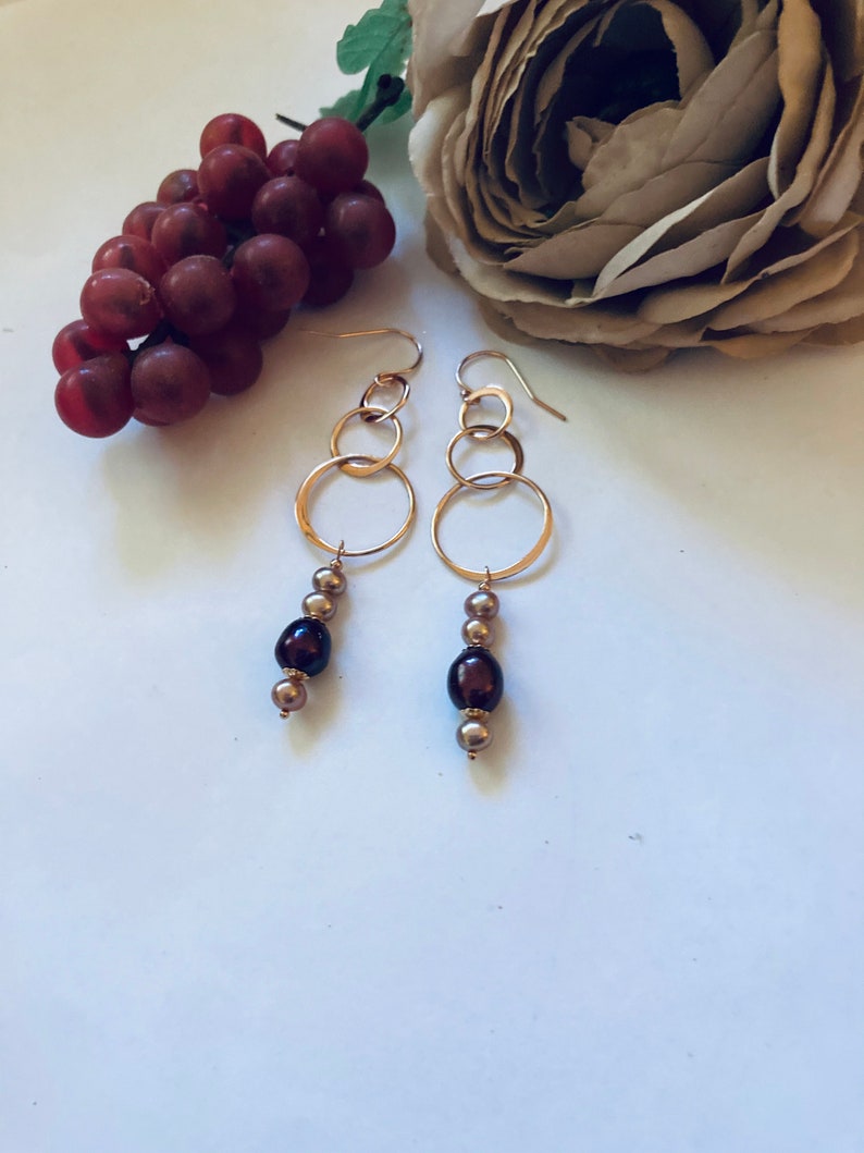 May include: Gold hoop earrings with a dangling chain of brown and gold beads.