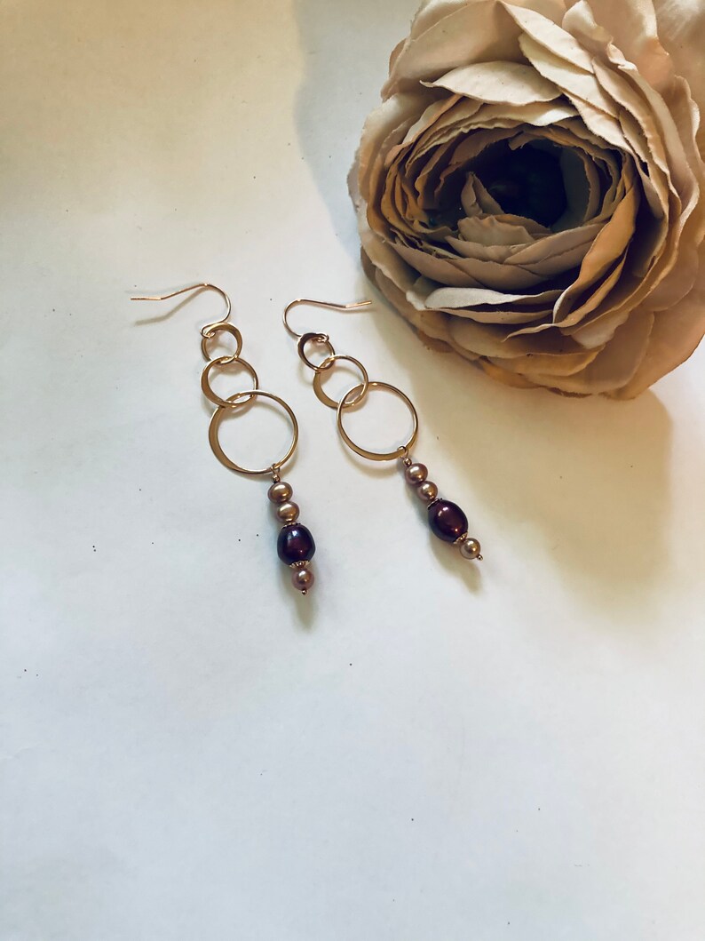 May include: Gold hoop earrings with a dangling chain of brown and gold beads.