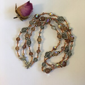 May include: A multi-strand necklace made of iridescent brown, gray, and clear glass beads. The necklace has a silver clasp.
