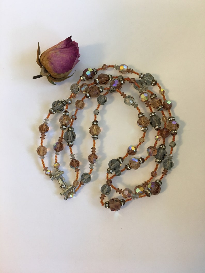 May include: A multi-strand necklace made of iridescent brown, gray, and clear glass beads. The necklace has a silver clasp.
