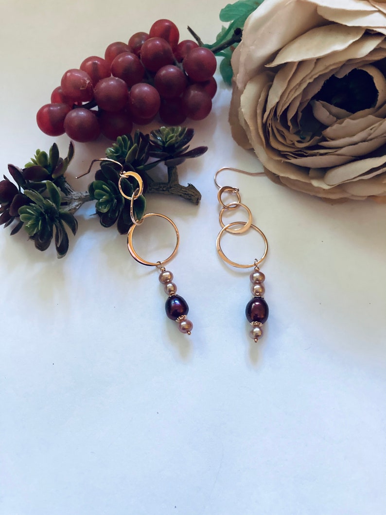 May include: Gold hoop earrings with three connected hoops and a dangling strand of brown and gold pearls.