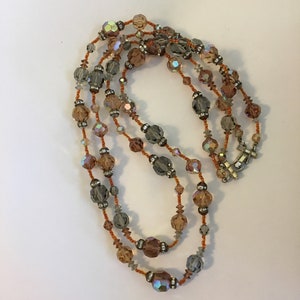 May include: A multi-strand necklace with iridescent brown, gray, and clear crystal beads.