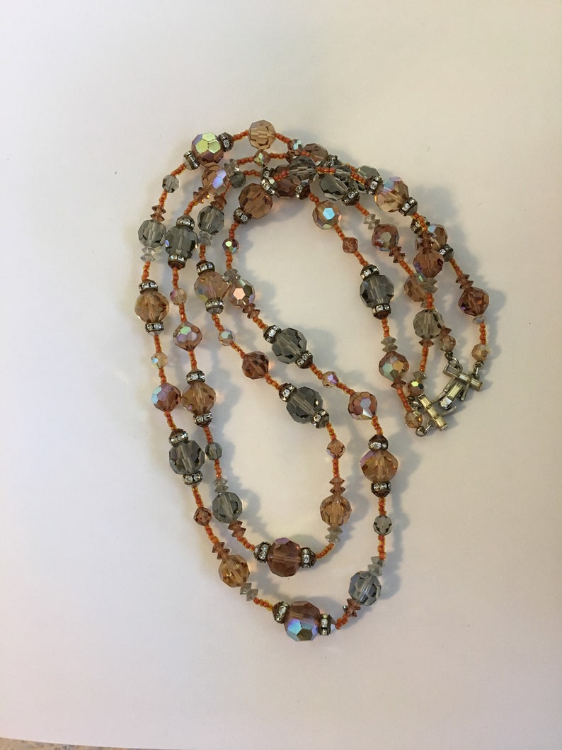 May include: A multi-strand necklace with iridescent brown, gray, and clear crystal beads.
