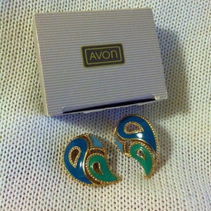 May include: A pair of blue and green paisley-shaped earrings with gold trim, in a white box with the word "AVON" printed on it.
