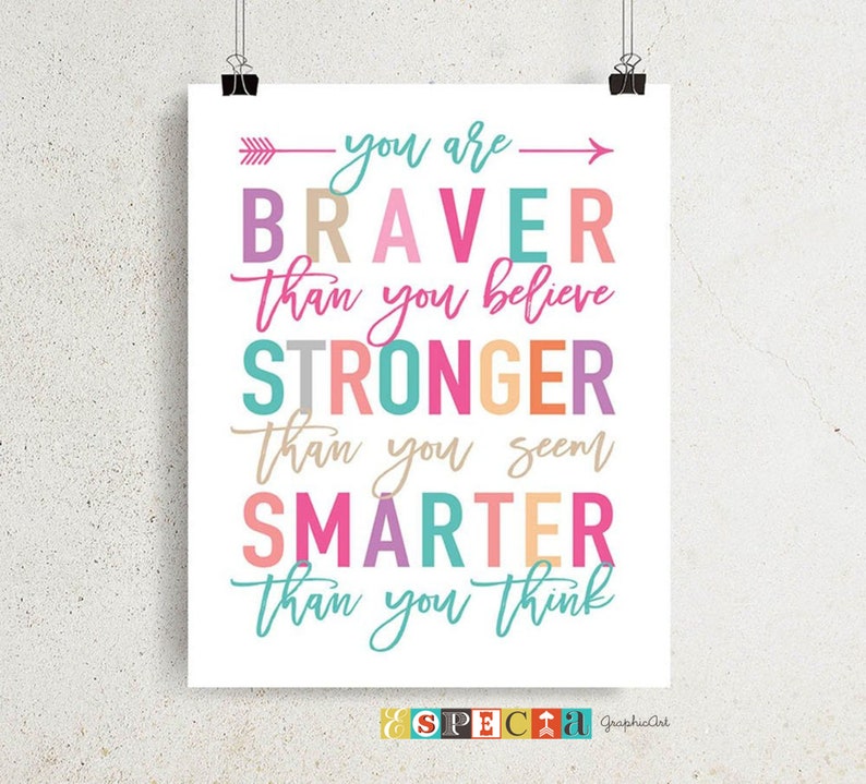 May include: A motivational poster with the words "you are BRAVER than you believe, STRONGER than you seem, SMARTER than you think" in various colorful fonts. The poster is held by two black binder clips.