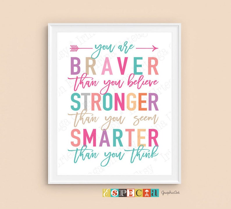 May include: A framed print with the words "you are BRAVER than you believe, STRONGER than you seem, SMARTER than you think" in colorful letters. The print has a white border and a light peach background.