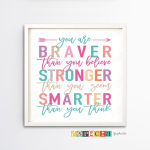 May include: A framed print with the words "You are Braver Than you believe, Stronger Than you seem, Smarter Than you think" in colorful text. The print has a white frame and a white background. The text is in various colors, including pink, teal, and orange.