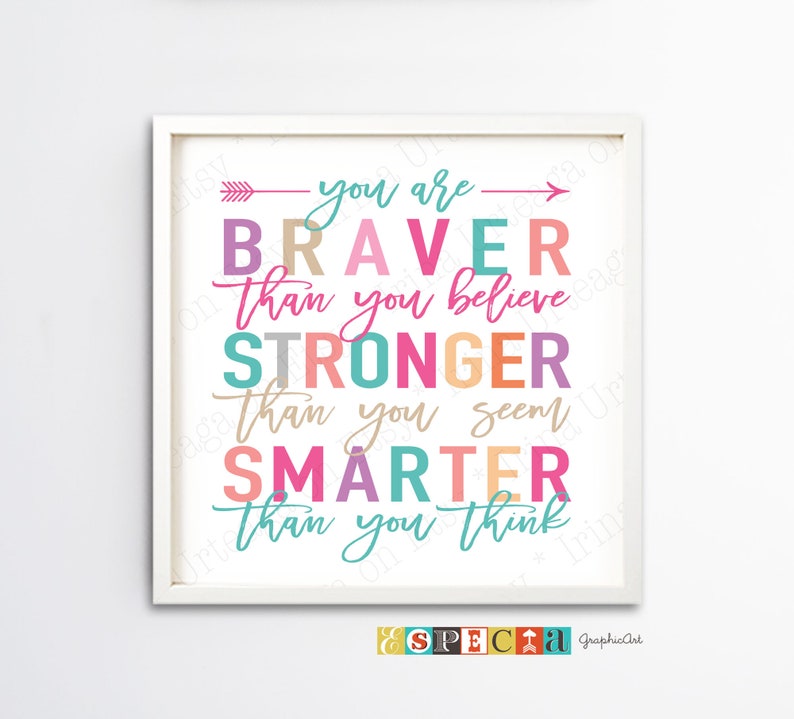 May include: A framed print with the words "You are Braver Than you believe, Stronger Than you seem, Smarter Than you think" in colorful text. The print has a white frame and a white background. The text is in various colors, including pink, teal, and orange.