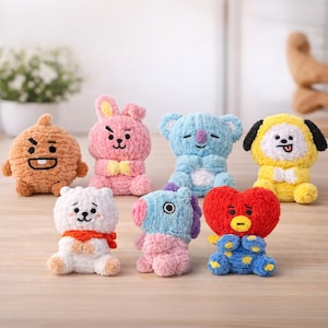 May include: A collection of seven colorful, plush character dolls. The dolls feature various shapes and colors, including brown, pink, blue, yellow, white, and red. Each doll has unique facial features and designs, with some wearing bows or scarves.