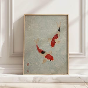 Puede incluir: Impresión artística enmarcada que presenta dos carpas koi en una escena acuática serena. Los peces están representados con marcas rojas, negras y blancas, sobre un fondo de agua azul claro con patrones arremolinados. La obra de arte está encerrada en un marco de madera natural.