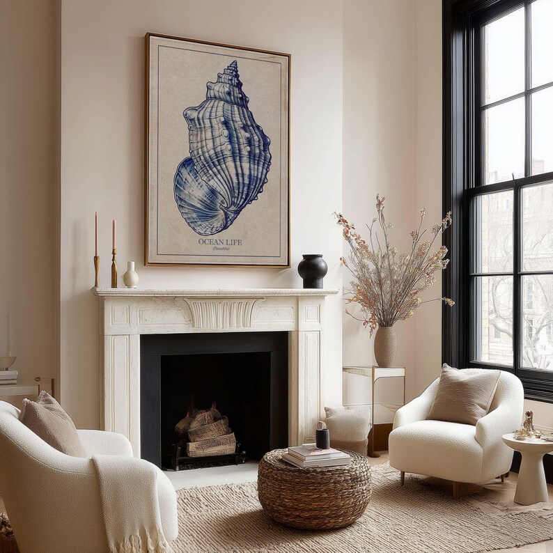 Blue vintage seashell illustration on warm beige paper, a wall art print hanging above a classic fireplace in a cozy neutral living room.