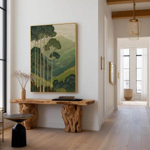 Forest trees over soft green mountains in a minimalist, calming wall art print, hung in a bright hallway above a rustic console.