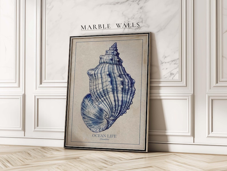 Detailed vintage seashell in blue on beige textured paper, an art print leaning against an elegant white paneled marble wall.