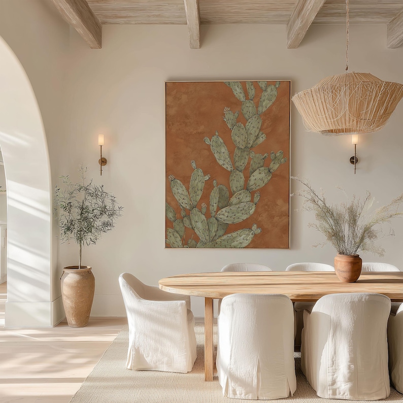 Warm prickly pear cactus art in muted green and terracotta, vintage botanical look, shown as a framed poster above a round dining table.
