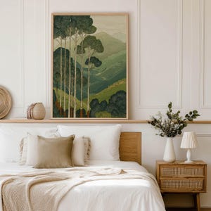 Layered green mountain valley with slender trees in a serene, vintage-style art print, displayed framed above a neutral bed.