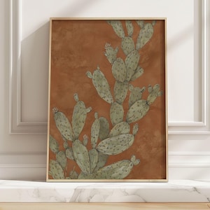 Prickly pear cactus in muted green on terracotta, vintage botanical style and calm mood, shown as a framed art print leaning on a marble ledge in sun.
