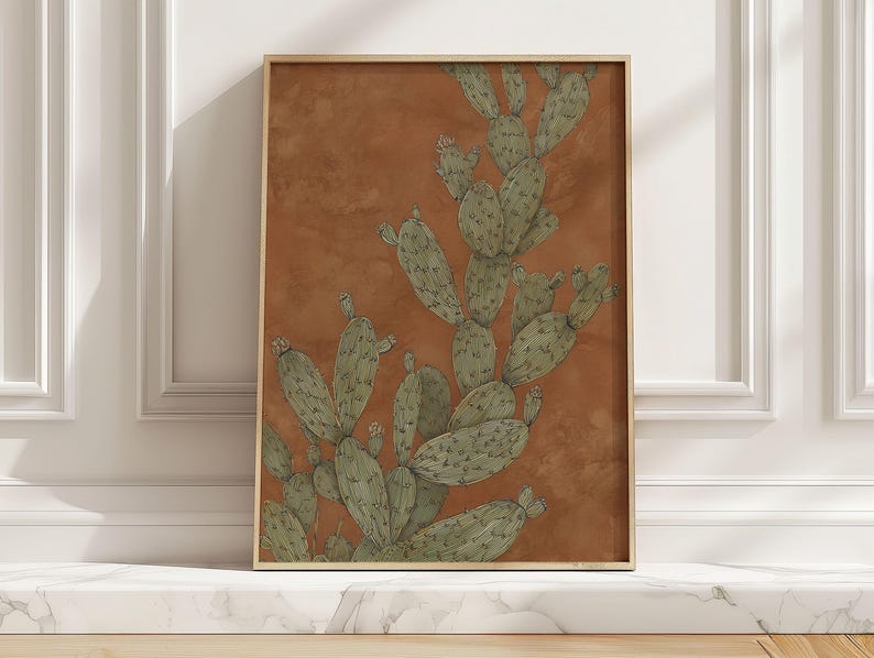 Prickly pear cactus in muted green on terracotta, vintage botanical style and calm mood, shown as a framed art print leaning on a marble ledge in sun.