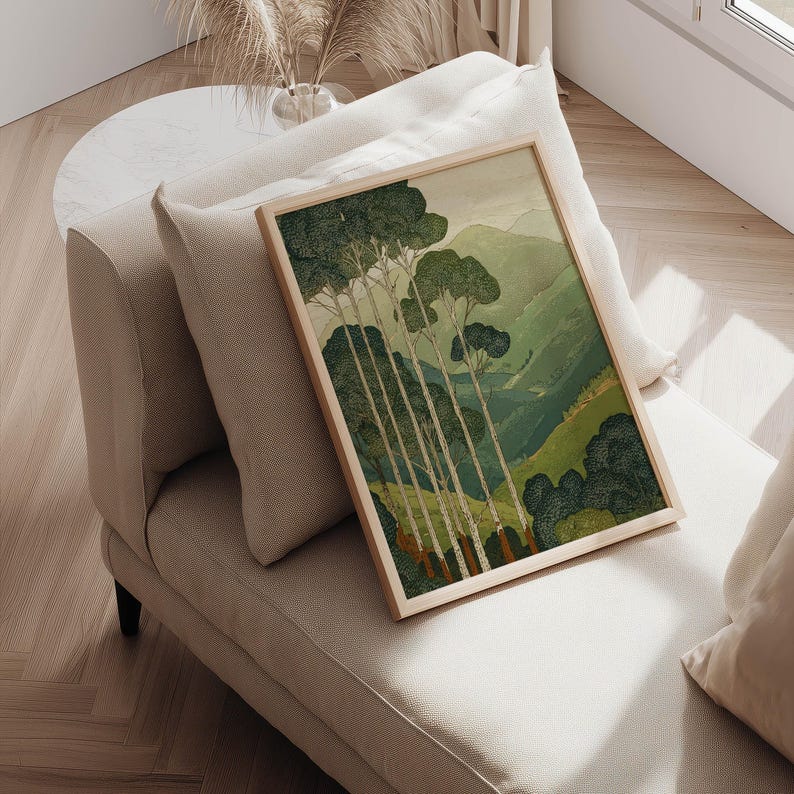 Tall trees against rolling green hills in a Japanese-inspired, tranquil wall art print, posed on a cushioned chair with sunlight nearby.