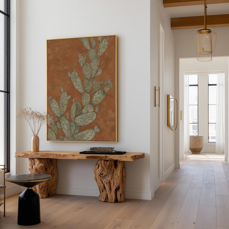Minimal prickly pear cactus illustration in green and brown, understated botanical style, hung as a framed wall art print in a bright hallway.