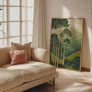 Quiet green landscape with tall tree trunks in a vintage-inspired, tranquil art print, shown leaning beside a sofa in warm window light.